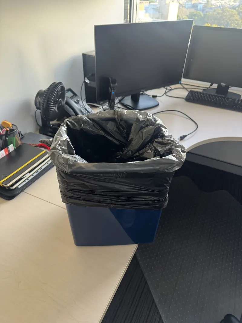 Overflowing office bin left unemptied by an untrained cleaner